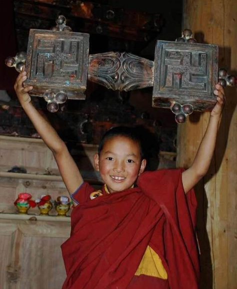 A young boy holds a wooden chakshing, symbol of Buddha Tonpa Shenrap Miwo