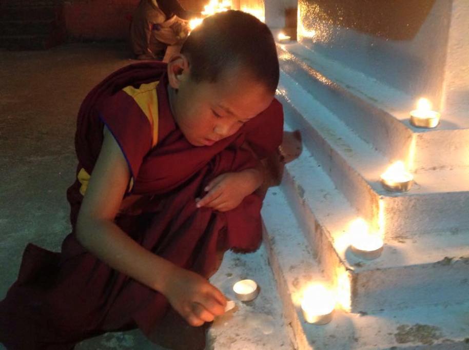young monk lighting candle at stupa